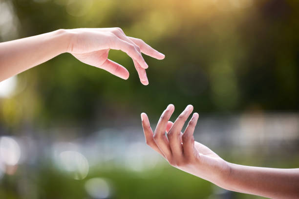 istock Shot of two unrecognizable people reaching for each other outside 1385074671