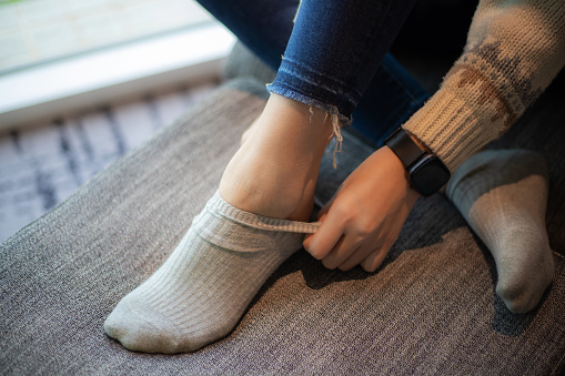 Close-up of woman putting on socks.