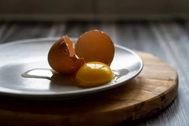 Eggyolk and broken eggshell on a plate