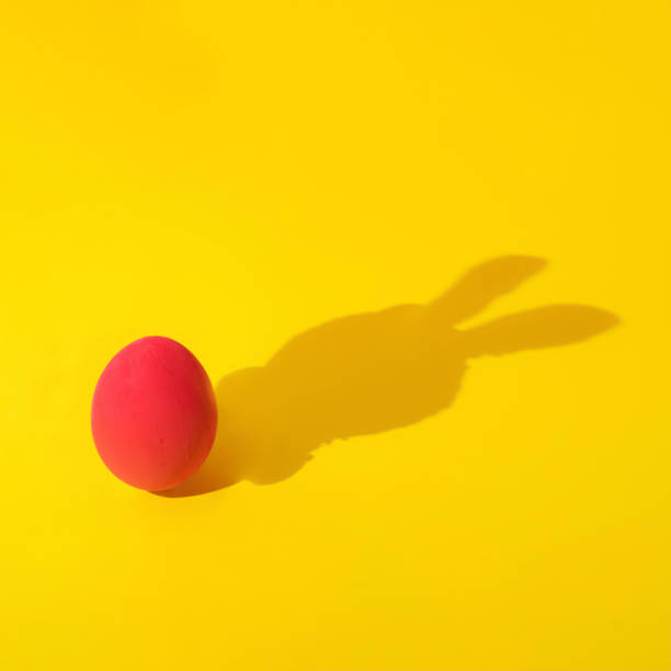 istock creative concept of red easter egg with rabbit shadow on yellow background . minimal composition. 1385078804