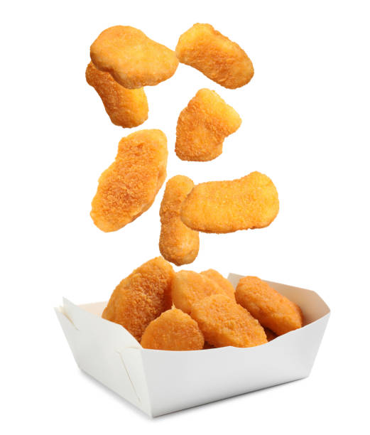 Fresh chicken nuggets falling into container on white background Fresh chicken nuggets falling into container on white background nuggets heat stock pictures, royalty-free photos & images