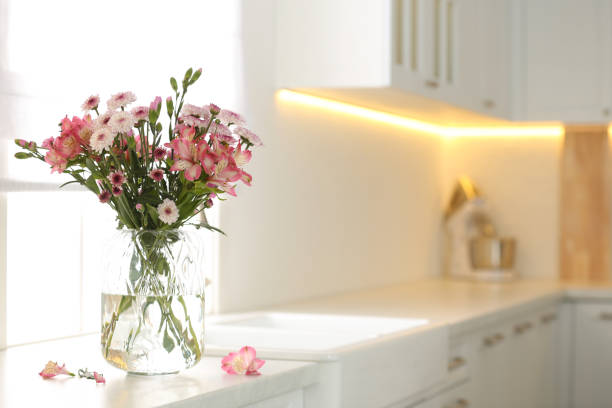 istock Vase with beautiful flowers on kitchen counter, space for text. Stylish element of interior design 1385080131
