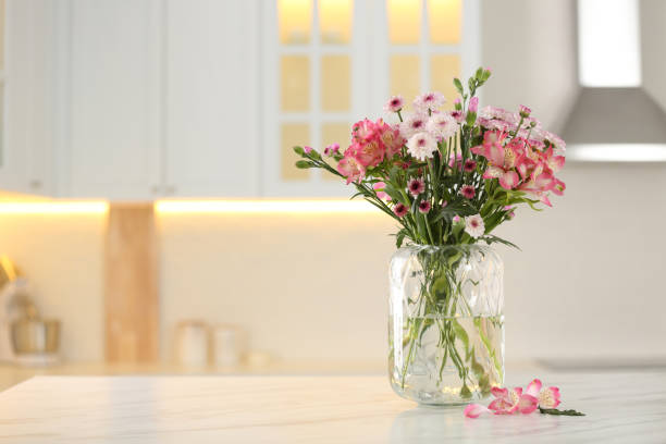 istock Vase with beautiful flowers on table in kitchen, space for text. Stylish element of interior design 1385080224