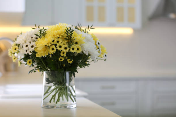 istock Vase with beautiful chrysanthemum flowers on countertop in kitchen, space for text. Interior design 1385080458