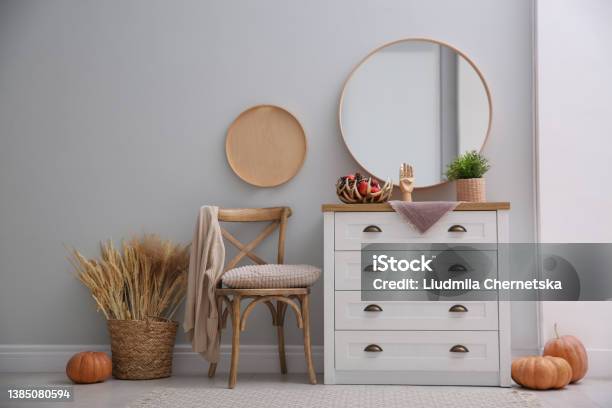 Round Mirror And Chest Of Drawers Near Grey Wall In Hallway Interior Design Stock Photo - Download Image Now