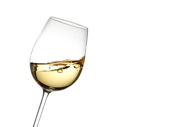 Sloped white wine glass on a white background On a white background, isolated, a tilted crystal glass filled with moving white wine which is observed frozen. On one side there is a lot of copy space. white wine photos stock pictures, royalty-free photos & images