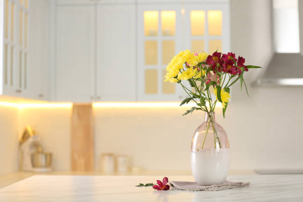 istock Vase with beautiful flowers on table in kitchen, space for text. Stylish element of interior design 1385083702