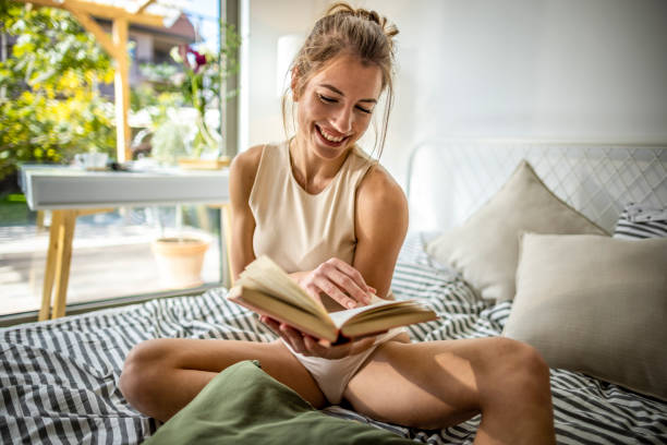 istock Beautiful Woman Reading a Book on her Bed 1385084948