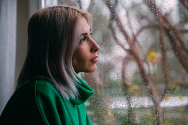 istock Depressed Woman Watching the Rain Through the Window 1385087449