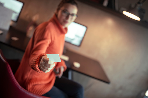 The young woman is blurred in the background. She holds a credit card in her hands.