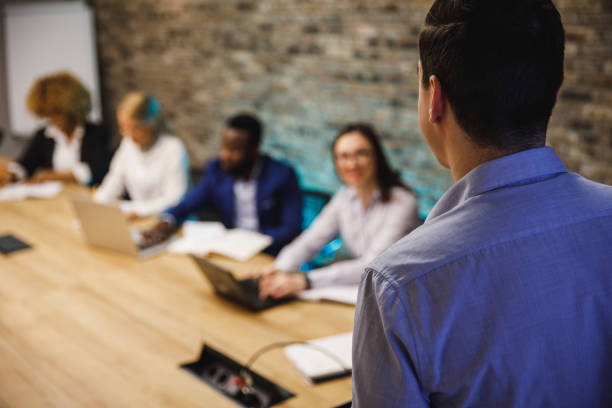 selective focus shot of businessman holding a presentation for his colleagues - over the shoulder view fotos imagens e fotografias de stock