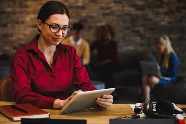 istock Young businesswoman sitting at her desk, using digital tablet 1385089495