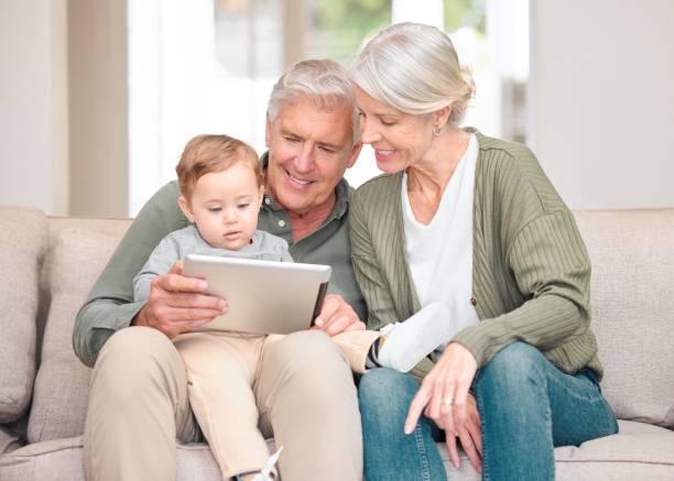 Cropped shot of an affectionate senior couple reading to their grandson while sitting on the sofa at home Look who came to visit real wife stories stock pictures, royalty-free photos & images