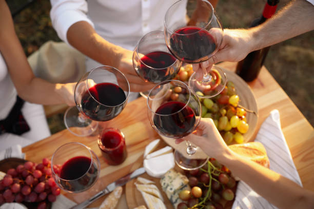 друзья держат бокалы вина за столом, крупным планом - vineyard стоковые фото и изображения