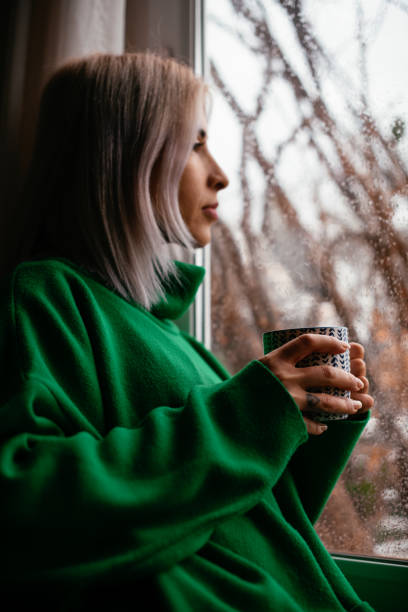 istock Depressed Woman Drinks Coffee by the Window 1385091260