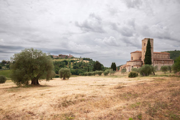 opactwo sant antimo (abbazia di sant'antimo), na nizinie wśród drzew oliwnych i cyprysów oraz na szczycie wzgórza w mieście castelnuovo dell'abate. toskania, włochy - abbazia di santantimo zdjęcia i obrazy z banku zdjęć