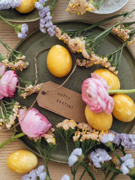 istock Yellow natural colored easter egg and flowers with text happy easter 1385093685