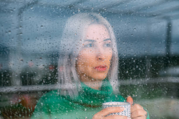 istock Depressed Woman Watching the Rain Through the Window 1385095081
