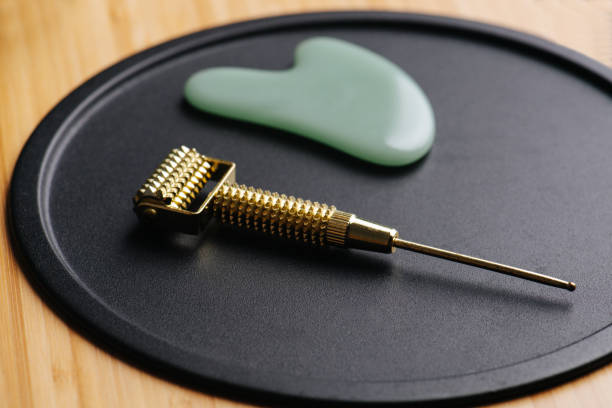 istock Gua sha metal tipped roller and a river stone on a black plate 1385095459