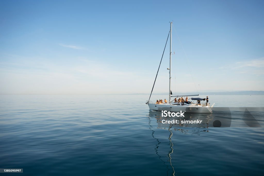 Friends sitting on sailboat Large group of friends sailing and having fun on boat in sunny day. Sailboat Stock Photo