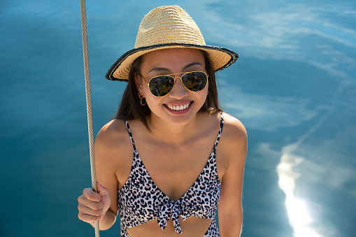 Portrait of young woman wearing sun hat while standing on boat deck during sunny day.