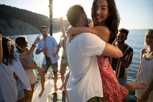 Young couple embrace each other with a hug as the greet their friends on boat.