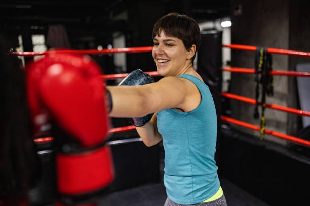 istock Cheerful female boxer having a training with coach in the boxing ring 1385096943