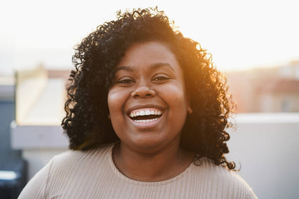 istock Young african woman smiling on camera with sunset on background - Focus on face 1385097049