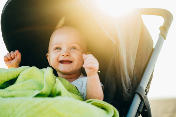 menino sentado em um carrinho de bebê na praia - carriage - fotografias e filmes do acervo