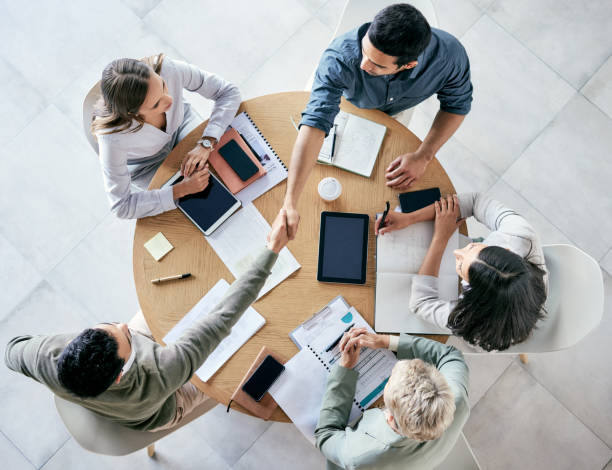 近代的なオフィスでのチームミーティング中に握手するビジネスマンのショット - office table ストックフォトと画像