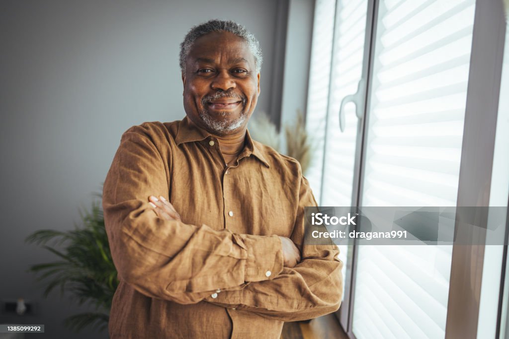 African American Senior Man at home Portrait. African American Senior Man at home Portrait. Smiling senior man looking at camera. Portrait of black confident man at home. Portrait of a senior man standing against a grey background Men Stock Photo