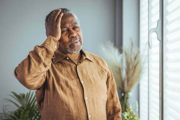 gros plan sur le visage d’un homme plus âgé des années 70 qui se masse les tempes et se tient la tête - mental health headache illness mental illness photos et images de collection