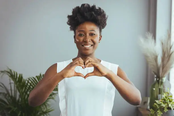 Photo of Cropped close up smiling grateful woman showing heart sign