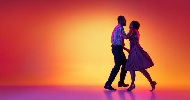 retrato de hombre y mujer emocionados, pareja de bailarines con atuendos de estilo retro vintage bailando lindy hop aislado sobre fondo amarillo y púrpura degradado. aviador - bailar el swing fotografías e imágenes de stock