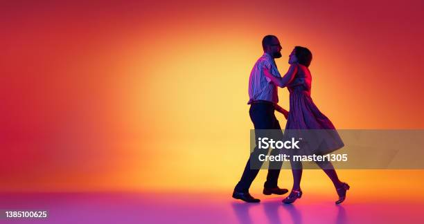 Portrait Of Excited Man And Woman Couple Of Dancers In Vintage Retro Style Outfits Dancing Lindy Hop Dance Isolated On Gradient Yellow And Purple Background Flyer Stock Photo - Download Image Now