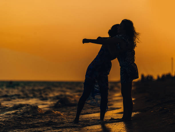 istock Young women walking on beach under sunset light 1385101077