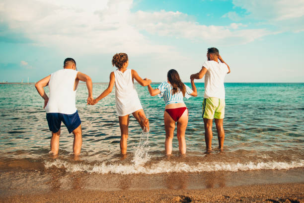 istock Image of four energetic people jumping at the beach 1385101426
