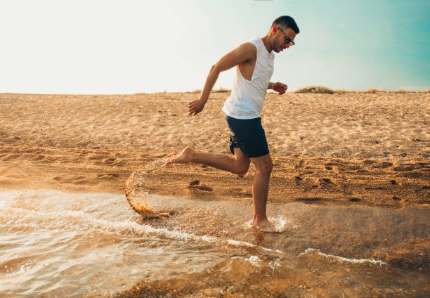 istock Image of young person running through the beach 1385101442