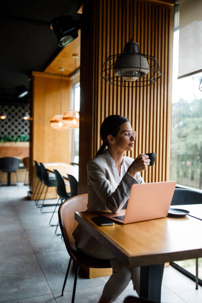 istock Young woman having coffee and using a laptop at a cafe 1385102020