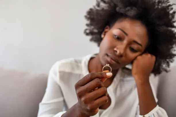 Upset african American girl hold wedding ring cry depressed with divorce, marriage dissolution, unhappy sad black young woman feel desperate breaking up. Family split, relationships problem concept