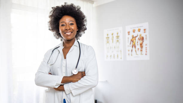 Portrait of professional confident young doctor in white coat Portrait of a confident doctor working in a hospital. African American Healthcare Professionals. Portrait Of Smiling Female Doctor Wearing White Coat With Stethoscope In Hospital Office female doctor stock pictures, royalty-free photos & images