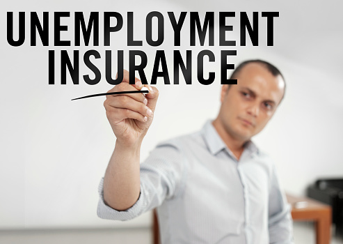 Businessman writing “Unemployment insurance” on a transparent screen