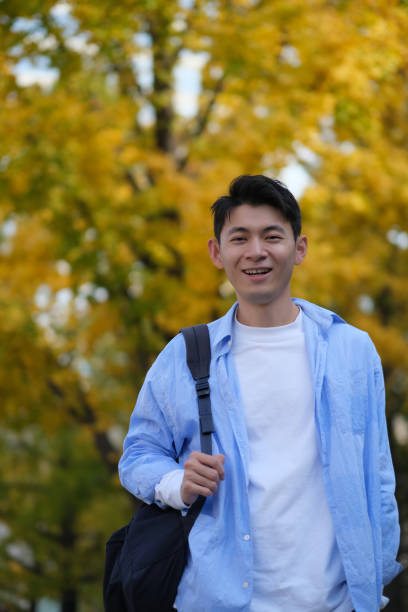 istock male college student carrying a shoulder bag and smiling at camera 1385108247