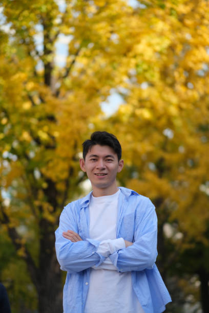 istock confident Asian young man at public park in autumn 1385108277