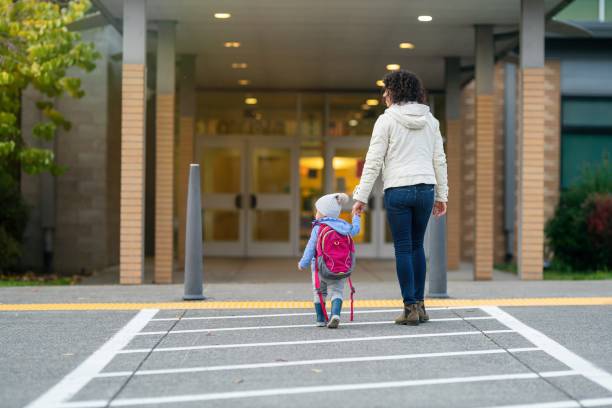 Mom dropping toddler daughter off at school stock photo