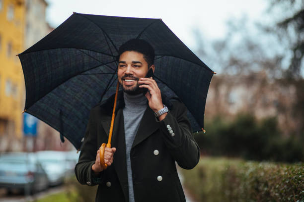 istock Afro businessman on rainy day using phone 1385112221
