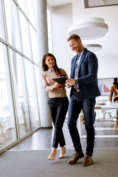 istock Young entrepreneur couple walking together and using digital tablet in the modern office 1385114301