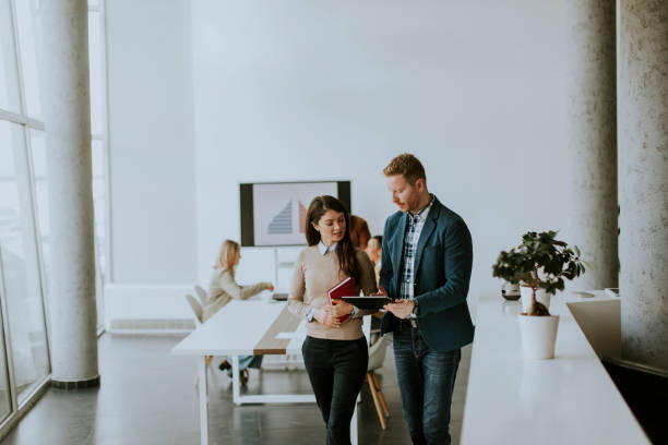 istock Young entrepreneur couple walking together and using digital tablet in the modern office 1385114302
