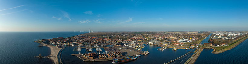 Aerial view on harbor of the former island of Urk at the shore of IJsselmeer in Flevoland, The Netherlands during a sunny early springtime day. Overhead drone view on the ships and quay.