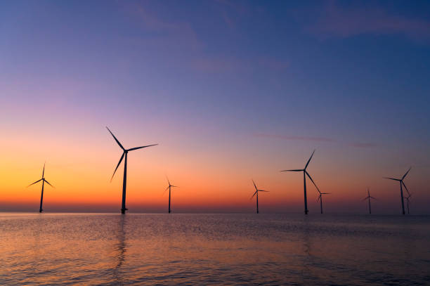 istock Wind turbines in an offshore wind park producing electricity during sunset. 1385114656